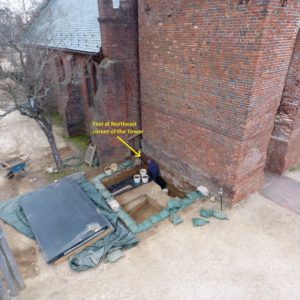 Aerial view of excavation unit next to brick church tower
