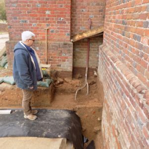 Staff examines excavations next to brick church wall