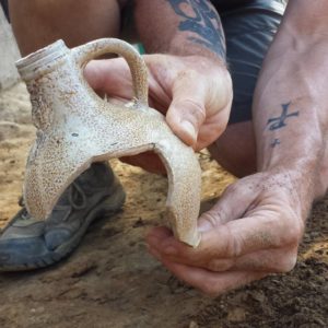 Archaeologist holding newly-excavated jug sherds