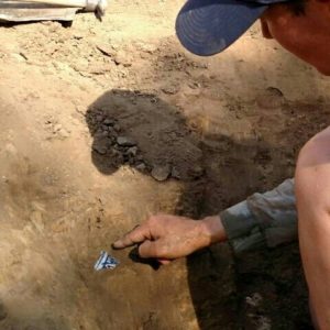 Archaeologist pointing to a ceramic sherd in situ