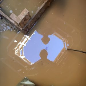 Two archaeologists reflected in well water
