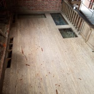 Wood floor with glass exhibit panels in brick church chancel