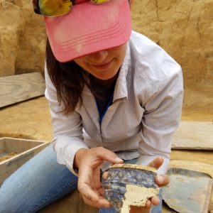 Archaeologist showing ceramic sherd to camera
