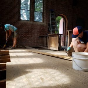 Students removing floor boards in brick church chancel
