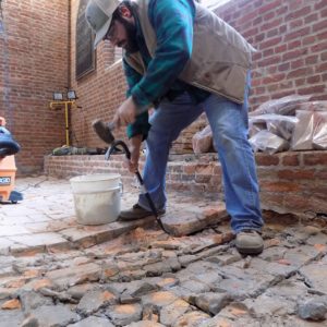 Archaeologist removing tiles from brick church floor
