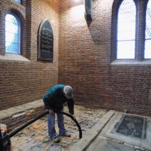 Archaeologist suctioning rubble from church chancel
