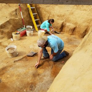 Archaeologists troweling in an excavation unit