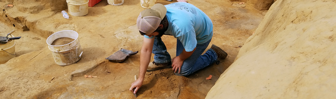 Archaeologist troweling in an excavation unit
