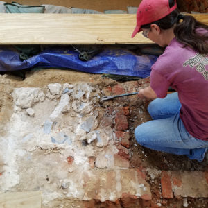Archaeologist removing mortar from floor
