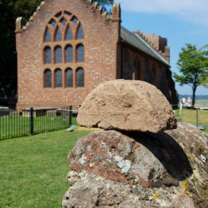 Half-round brick place on top of brick wall in front of brick church