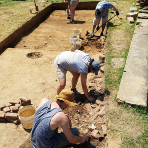 Excavators remove bricks from side of unit