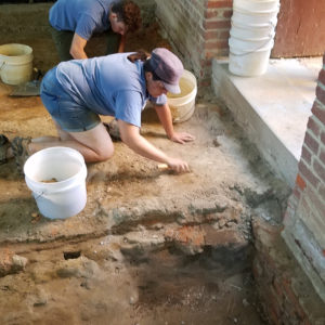 Excavators work near doorway to brick church