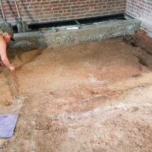 Archaeologist excavates dirt floor of brick church