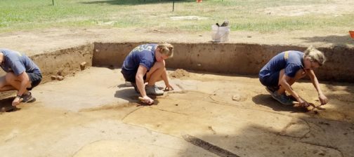 Archaeologists excavating above outlined grave shafts