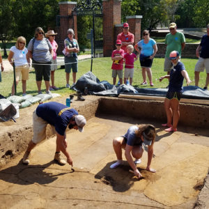 Archaeologists clean unit while another talks to visitors