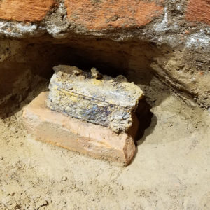 Small metal box buried under brick wall