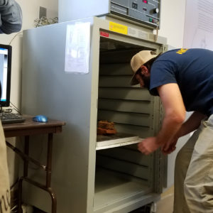 Archaeologist inserting metal box into x-ray machine
