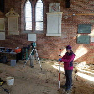 Archaeologists using total station inside a brick church