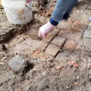 Archaeologist excavates brick and dirt church floor