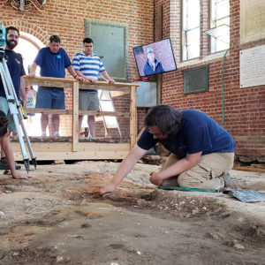 Two archaeologists excavate in brick church