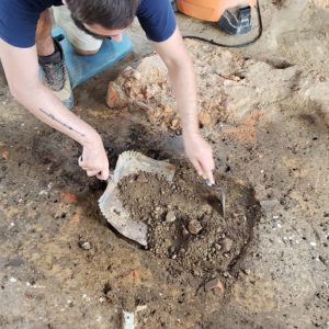 Archaeologist excavates dirt floor