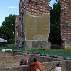 Archaeologists excavate in front of brick ruins