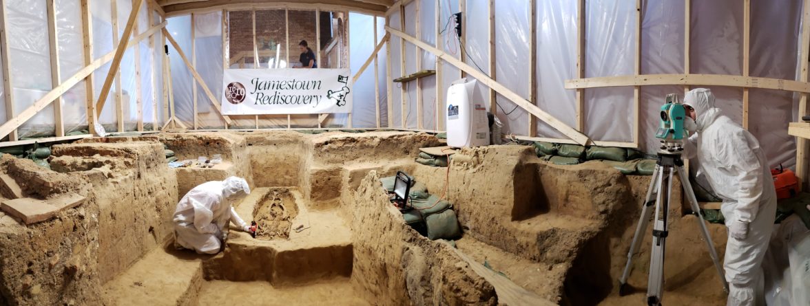 Archaeologists in Tyvek suits excavate and record burial