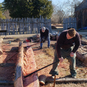 two men prying apart two halves of a split log