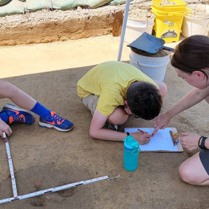 Staff Archaeologist Natalie Reid helps a camper document a feature.