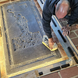 Director of Collections and Conservation Michael Lavin cleans the Knight’s Tomb ledger stone.