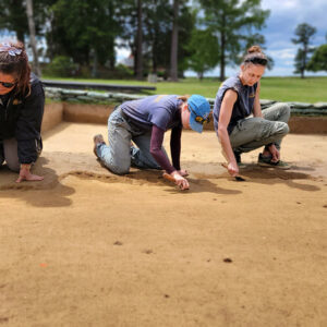 Archaeologists Hannah Barch, Natalie Reid, and Anna Shackelford excavate one of the north field squares bit by bit.