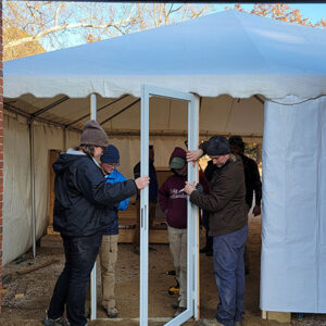 The archaeological team installs a door for the ticketing tent.