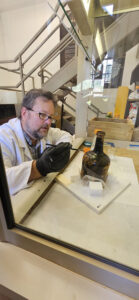 Senior Conservator Dr. Chris Wilkins applies a solution of B-72 diluted with acetone to one of the Mount Vernon cherry bottles. This will strengthen and protect the outer layers of the bottle.