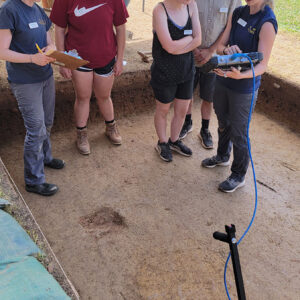 Staff Archaeologist Natalie Reid and Archaeological Intern Katherine Griffith help field school students Hope Clark, Madison Viars, and Richard Fallon conduct a GPR survey of a burial.