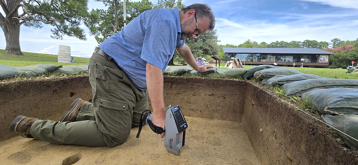 Senior Conservator Dr. Chris Wilkins uses the portable X-ray fluorescence machine to test portions of the soil in the boring location near the Dale House.