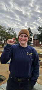 Staff Archaeologist Caitlin Delmas holds a Nueva Cadiz bead discovered in the cellar excavations.