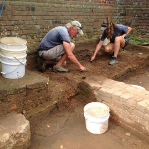 Archaeologists excavating next to brick church wall