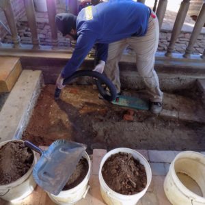 Archaeologist suctioning within excavation unit