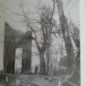 Black and white photograph of church tower ruins and yard
