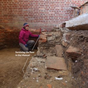 Archaeologist kneeling next to excavated tile floor