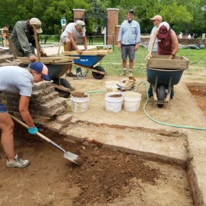 Students and staff excavating with shovels and screening artifacts