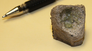 crucible fragment next to a pen for scale