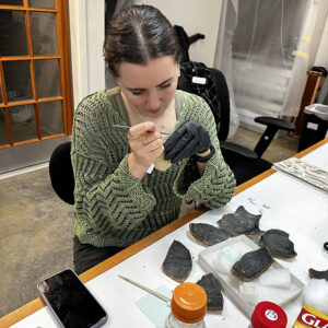 Amanda cleaning an olive jar fragment with a scalpel.