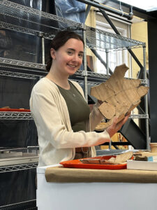Curatorial Intern Amanda Nedell holds a large section of the Spanish olive jar she mended this spring.