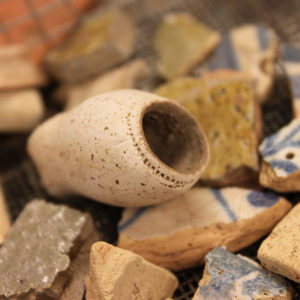 pipe bowl and assorment of ceramic sherds in a screen