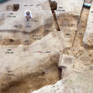 Aerial view of archaeologists standing next to excavated features with overlaid labels