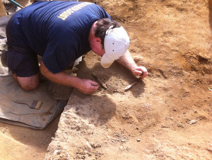 archaeologist using a pick to excavate an artifact