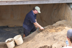 Archaeologist scrapes soil with a trowel