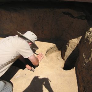 Archaeologist excavating a posthole
