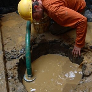 Archaeologist pumping water out of an excavated well